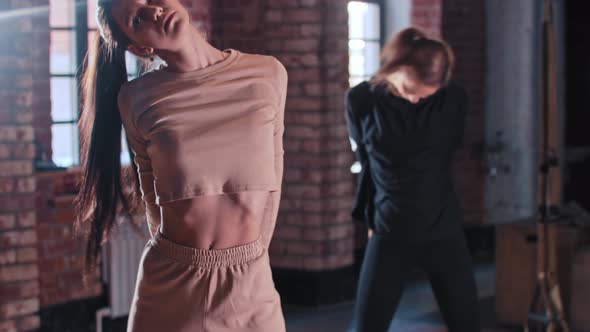 Two Women Warming Up Together in the Gym  Stretching Hands and Leaning Down alt
