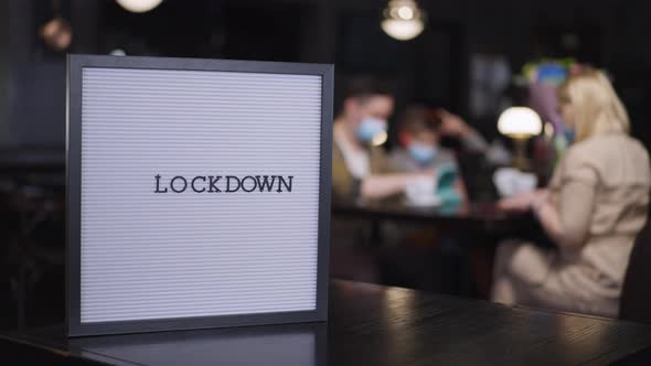 Closeup Lockdown Announcement in Restaurant with Blurred Family in Face Masks Dining at Background alt