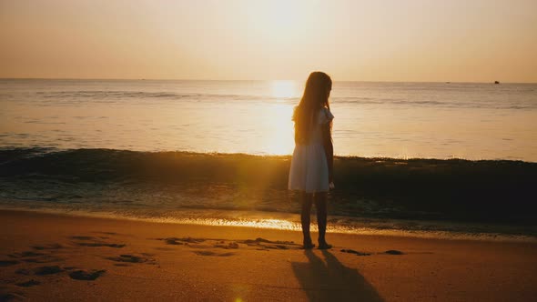 Idyllic Back View Shot of Happy Little Girl Watching Incredible Sunset on Epic Golden Ocean Beach alt