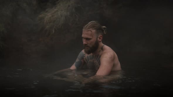 A Male Model Sits Relaxed on a Hot Bath By the Spring alt