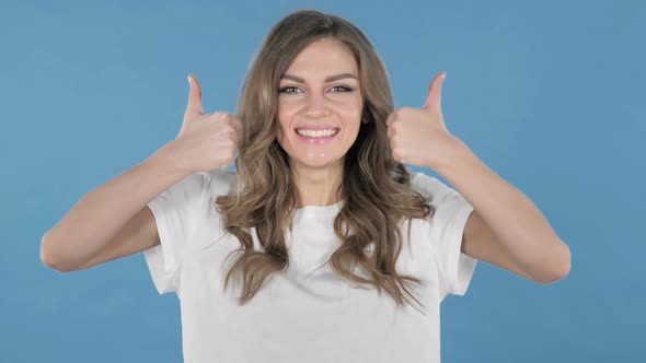Young Girl Gesturing Thumbs Up Isolated on Blue Background alt