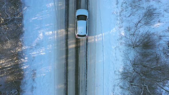 Close Up of White Car Riding Through Snowy Forest Road alt