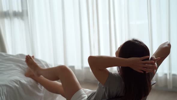 Young Asian woman relaxing in the bedroom in the morning
