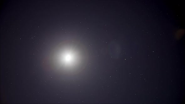 Time lapse: brightly shining moon and stars in night sky 4K