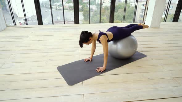 Slim sporty girl doing exercises with fitness ball alt