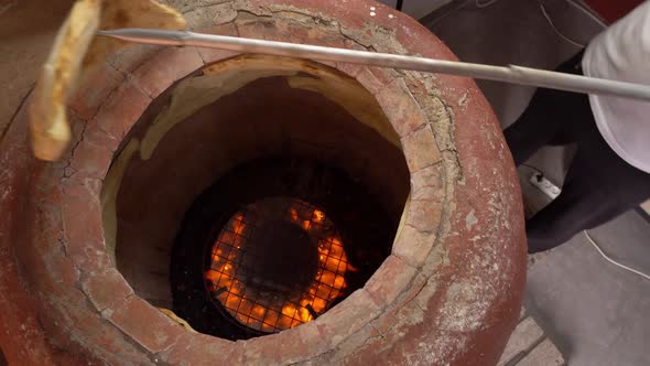 Baker making Turkish lavash in tandoor, clay oven. Baking process. alt
