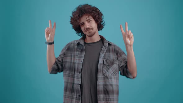 Young Hipster with the Fingers of Both Hands Shows the Sign of Peace alt
