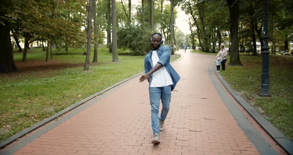 Happy Dancing Afro-American in Earphones in Park