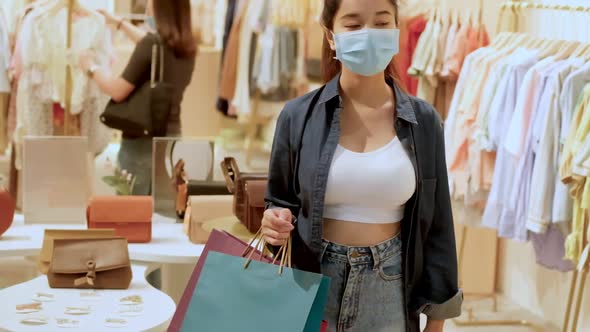 Asian woman wearing face mask. Happy woman with shopping bags enjoying in shopping