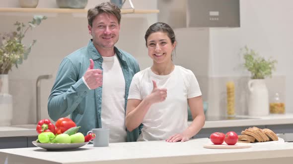 Mixed Race Couple Showing Thumbs Up Sign in Kitchen alt
