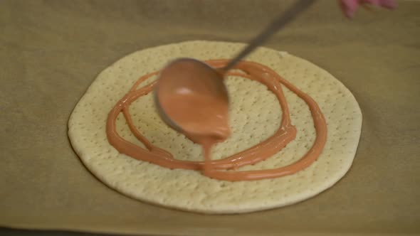 Woman Is Spreading Tomato Sauce on Pizza Dough with Ladle
