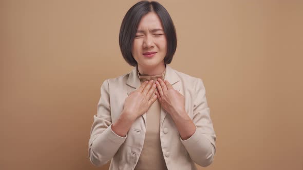 Asian business woman was sick with fever standing isolated over beige background. 4K video