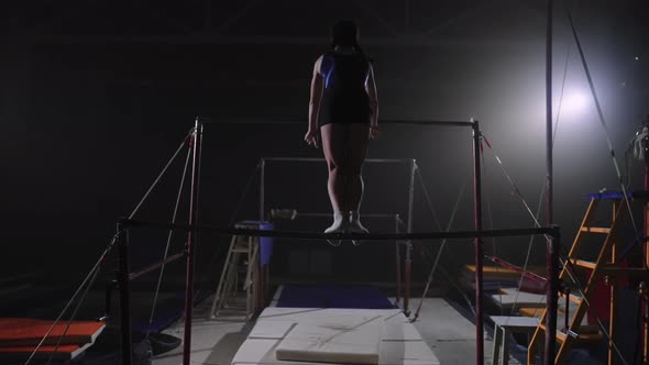 Training of Teen Girl Gymnast on Uneven Bars in Sports Hall Artistic Gymnastics Slow Motion alt