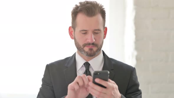 Young Businessman Browsing Internet on Smartphone alt