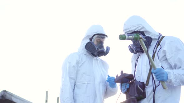 Two Scientists in Protective Suits and Masks and Make Measurements of Radiation Against the alt