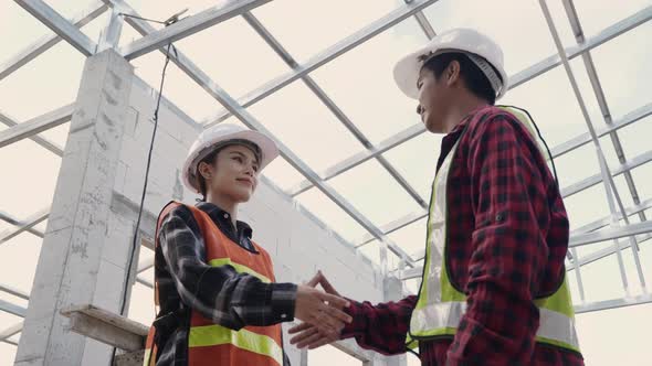 Asian architect engineer worker woman  man in protective helmet and uniform shaking hands alt