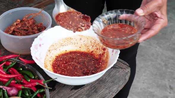 Food preparation, person fills glass bowl with fresh Spicy sauce - Thai Cuisine alt