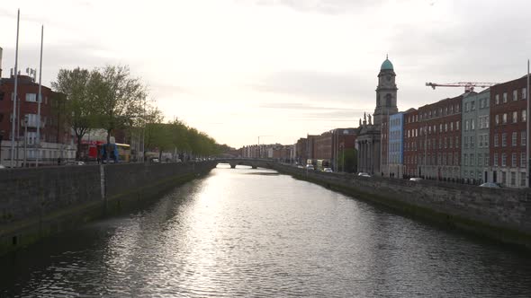 Liffey River With Traffic And Buildings On Both Sides At Late Evening In Dublin City, Ireland. - wid alt