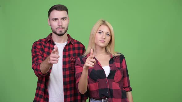 Young Couple Pointing to Camera Together