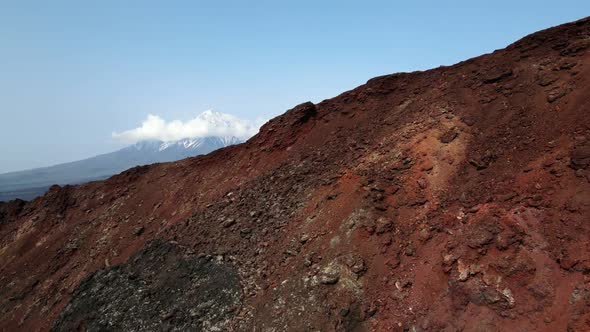 red mountain with a view of snow volcanoes