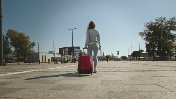 A Young Woman is Walking Through the Square Near the Train Station alt