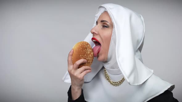 Passionate Woman in Nun Costume Licking Burger Smiling Looking at Camera alt