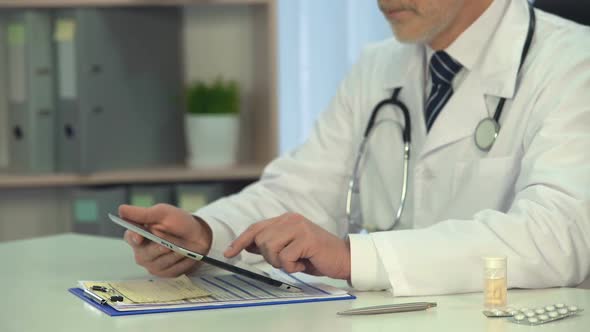 Male Physician Scrolling Information on Tablet, On-Line Consultation, Healthcare alt