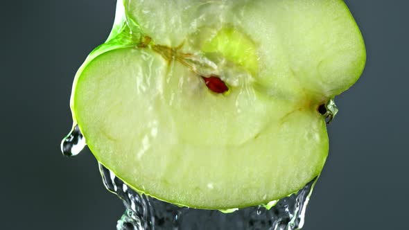 Super Slow Motion Detail Shot of Flowing Water From Apple Slice on Black Background at 1000Fps alt