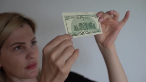 Woman Holding Dollar Bill and Looking at It with Watermarks Closeup