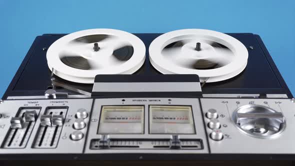 Rewinding Tape On An Old Reel To Reel Tape Recorder On A Blue Background.