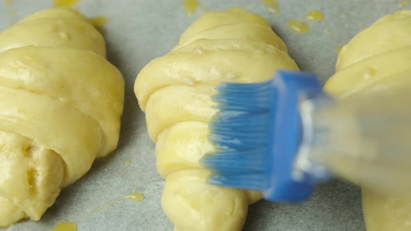 Close Up Applying of an Egg Yolk with Silicone Brush on Italian Croissants alt