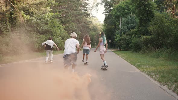 Group of Four Skaters Ride Through the Park with a Smoke Bomb Attached to the Board alt