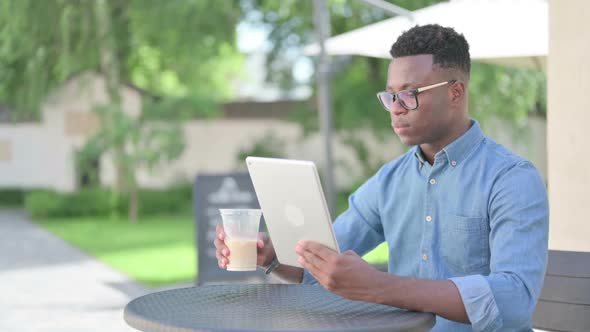Attractive African Man Using Tablet in Outdoor Cafe alt