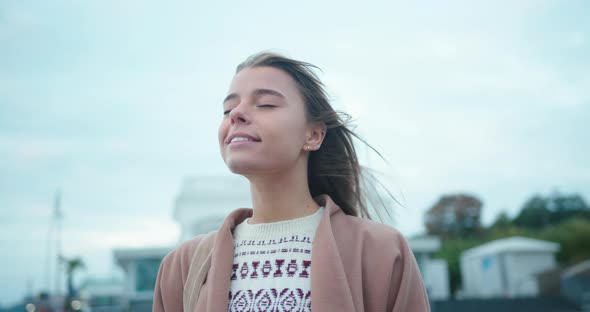 Woman Enjoys Windy Weather on Empty Street in Evening
