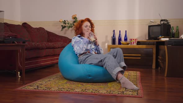 Retro Woman Sitting on Bag Chair Enjoying Taste of Cappuccino Smiling Drinking in Slow Motion alt