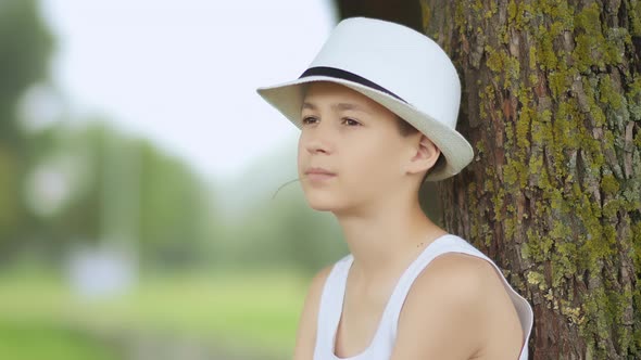 Funny Farmer Boy in a Hat Sits in the Park and Thinking About Something