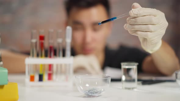 Employee Drops Dark Blue Liquid in Bowl with Crystals in Lab alt