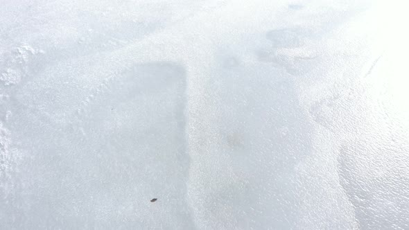 Ice on lake surface under sun light 4K drone footage alt