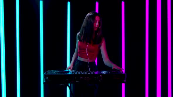 Portrait of a Young Pretty Woman in Big Red Headphones Dances and Mixes Music at the DJ Turntable alt