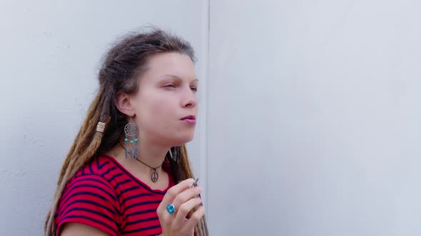 Girl Sits on Balcony or Veranda of House Smokes