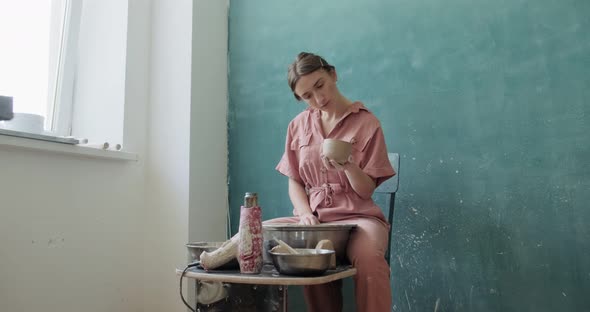 Female Potter Sitting and Makes a Cup. Woman Making Ceramic Item. Pottery Working, Handmade and alt