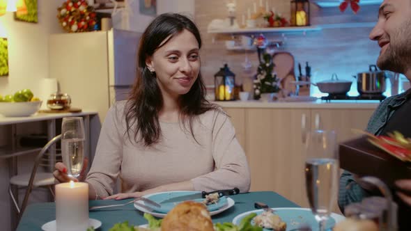 Woman Receiving Present Box From Man at Festive Dinner alt