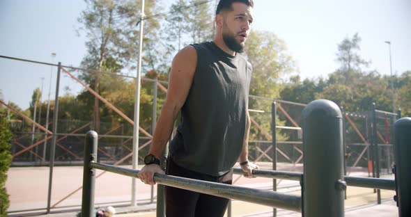 The Guy Warms Up Stretches His Musclesand Then Does Exercises on Parallel Bars alt