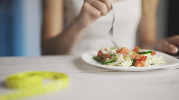 A Woman is Eating Fresh Vegetable Salad in Her Kitchen alt