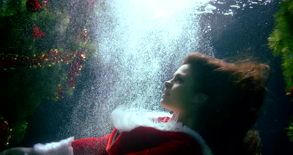 Young Woman Is Immersing Under Water Near Christmas Tree in Pool, New Year alt