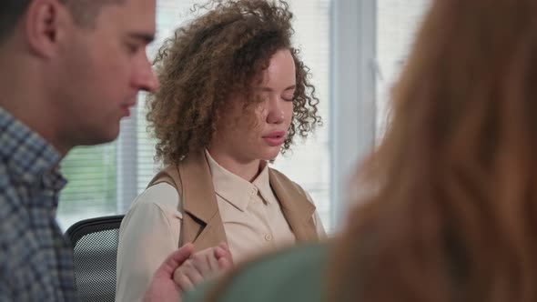 Portrait of Young Woman Holding Hands of Friends and with Closed Eyes Prays to God Then Applauds alt