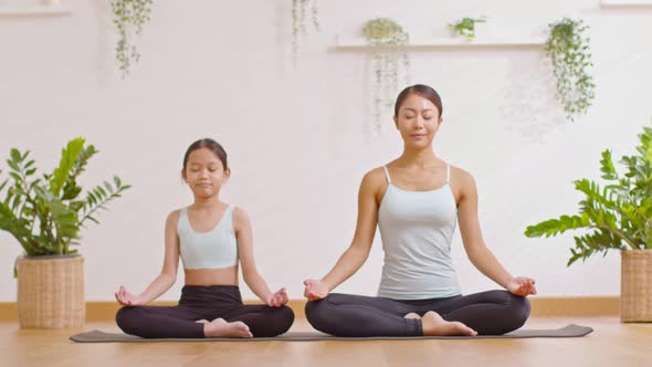 Healthy couple mom and little girl doing yoga exercise on yoga mat at home.Female mother and daughte alt