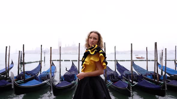 Woman Wearing Evening Dress Stands Near Venetian Gondolas alt