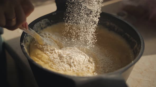 Closeup of a Woman Stirring the Dough in a Saucepan Adding Flour Through a Sieve