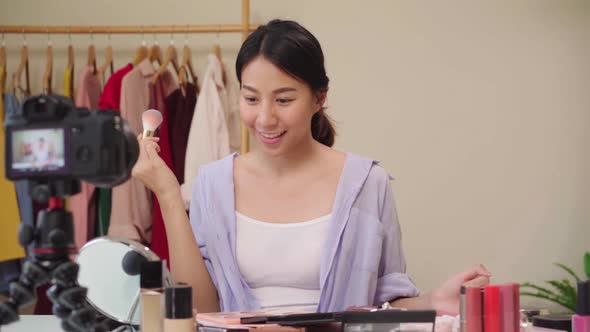 Beauty blogger present beauty cosmetics sitting in front camera for recording video Asian woman. alt